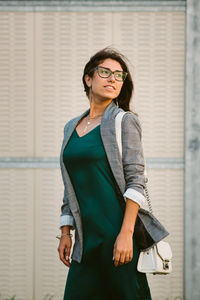 Young woman standing against wall