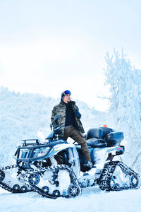 Full length of man on vehicle over snow covered land