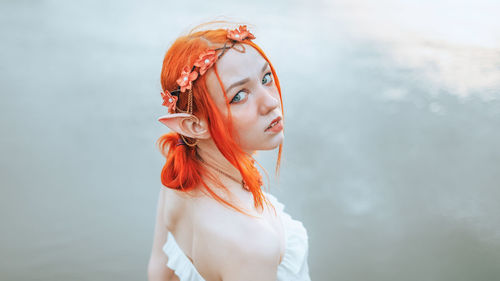 Portrait of young woman standing against wall