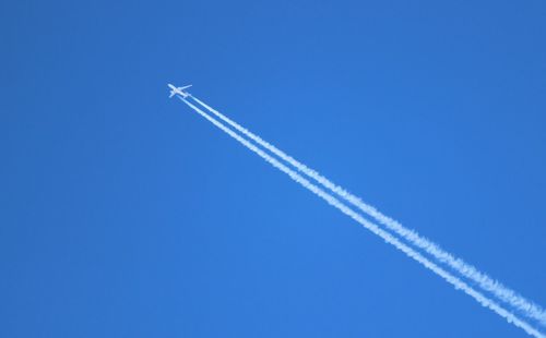 Low angle view of airplane flying against clear blue sky