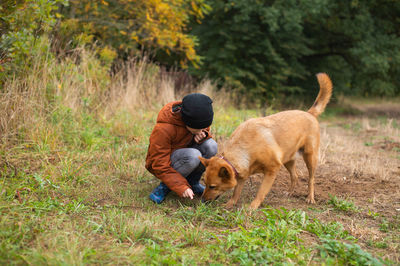 A boy digs the ground with a big red dog