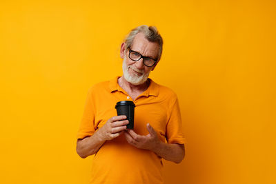 Portrait of woman using mobile phone against yellow background