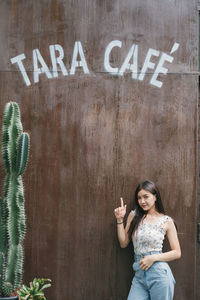 Portrait of woman standing by text on wall