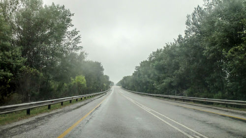 Road amidst trees against sky