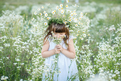 Young woman holding flower in field