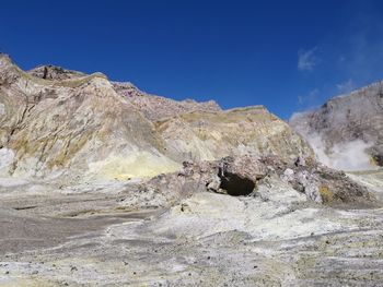 Rock formations on landscape against blue sky