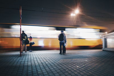 Rear view of people walking on illuminated subway