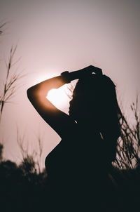 Portrait of silhouette woman photographing against sky during sunset
