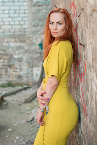 Portrait of woman standing by wall