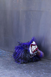 Purple mask on footpath against wall