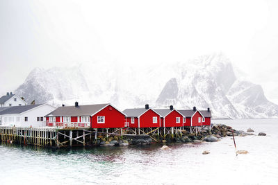 Houses on snow covered field by mountain against sky