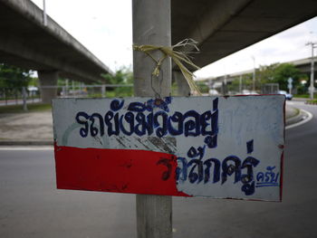 Close-up of information sign on pole against bridges on road