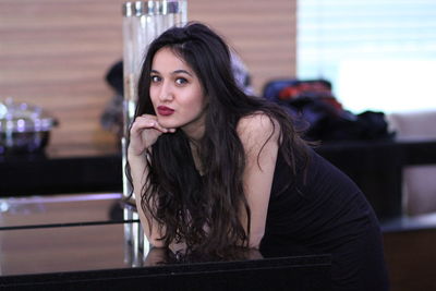 Portrait of beautiful young woman standing by table