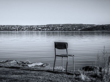 Empty chair against calm lake