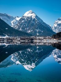 Scenic view of lake and snowcapped mountains against blue sky