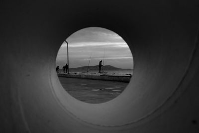  people on road seen through arch of perspective 