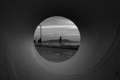  people on road seen through arch of perspective 