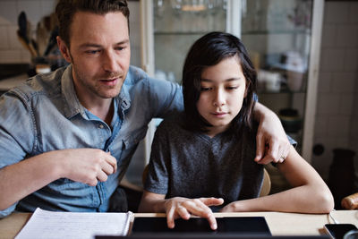 Son using laptop by father while doing homework at home