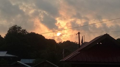 Low angle view of silhouette trees and buildings against sky during sunset