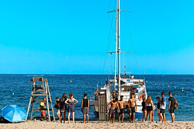 People on beach against blue sky