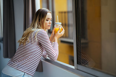 Side view of young woman drinking glass