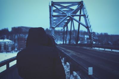 Rear view of person standing on bridge during winter