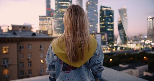 Rear view of woman standing by buildings in city