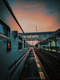 Train at railroad station against sky during sunset
