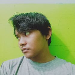 Portrait of young man looking away against wall