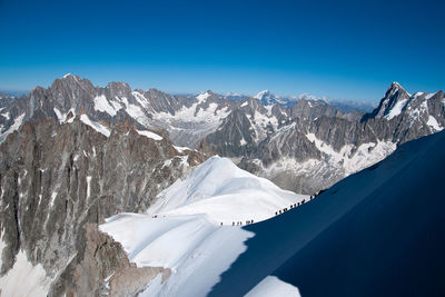 Scenic view of snowcapped mountains against blue sky