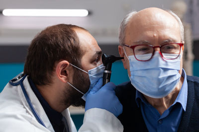 Doctor wearing mask examining patient ear