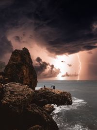 Rock formation in sea against sky during sunset