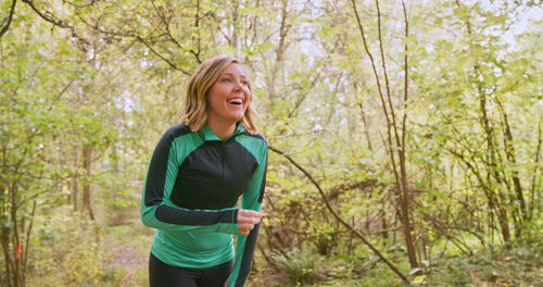 Smiling young woman exercising in forest