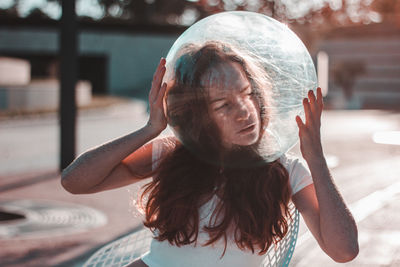 Close-up of young woman wearing glass container outdoors