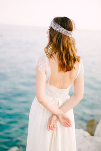 Rear view of bride looking at sea against sky