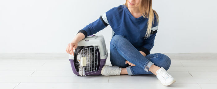 Midsection of woman sitting on floor against wall