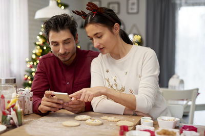 Couple looking at mobile phone while enjoying christmas 