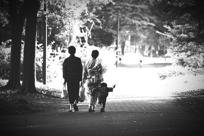 Rear view of people walking on road in park