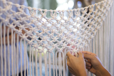 Cropped hands of woman making design with white strings