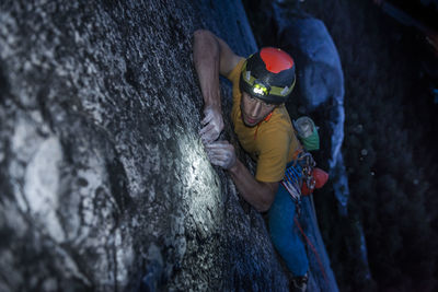 Top view man rock climbing at night above the sea and highway