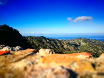 Scenic view of mountain by sea against blue sky