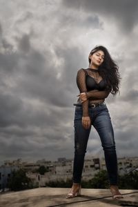 Full length of young woman standing against sky