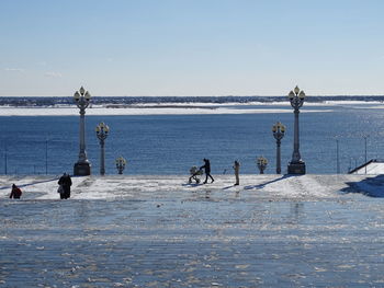 People on beach against clear sky