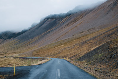 Road leading towards mountains against sky