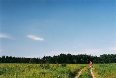 Rear view of woman on grassy landscape against sky