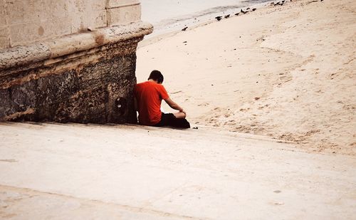 Rear view of man sitting on steps at beach