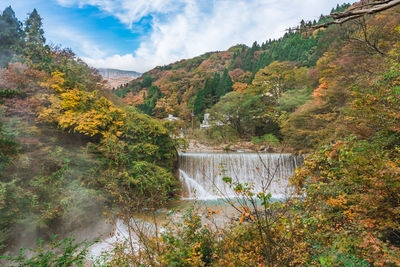 Scenic view of waterfall against sky during autumn