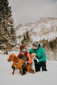 People amd dogs skiing on snow covered field