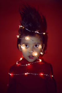 Christmas boy child in a garland at christmas on a red background in a sweater