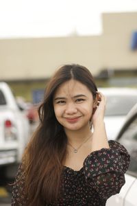 Portrait of smiling young woman standing against car